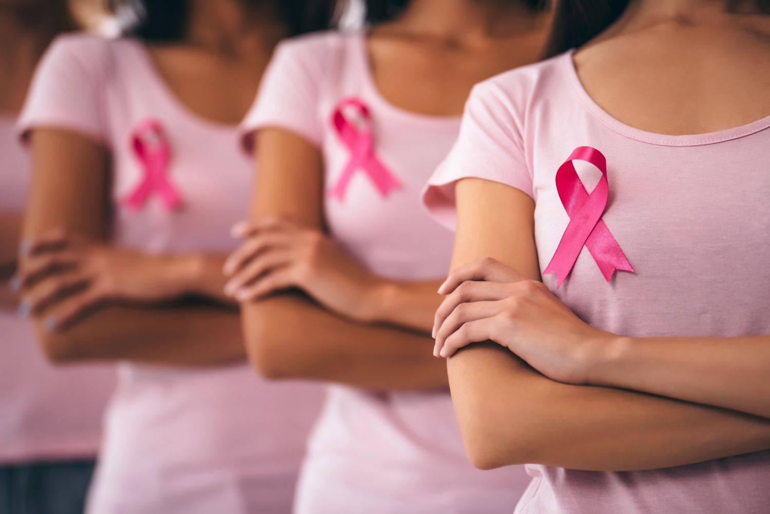 Mehrere Frauenoberkörper mit rosa Brustkrebs-Schleifen
